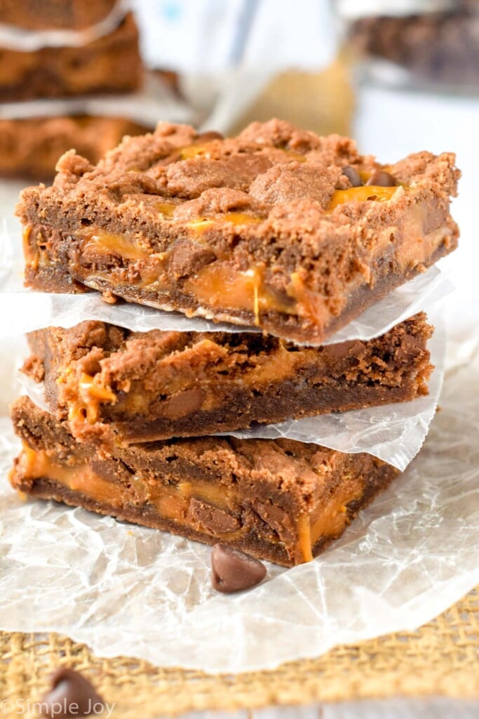 individual caramel brownies stacked with wax paper separating.