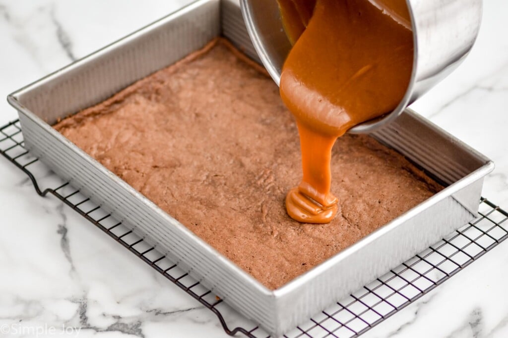 saucepan of caramel sauce pouring into a pan of brownies to make caramel brownies