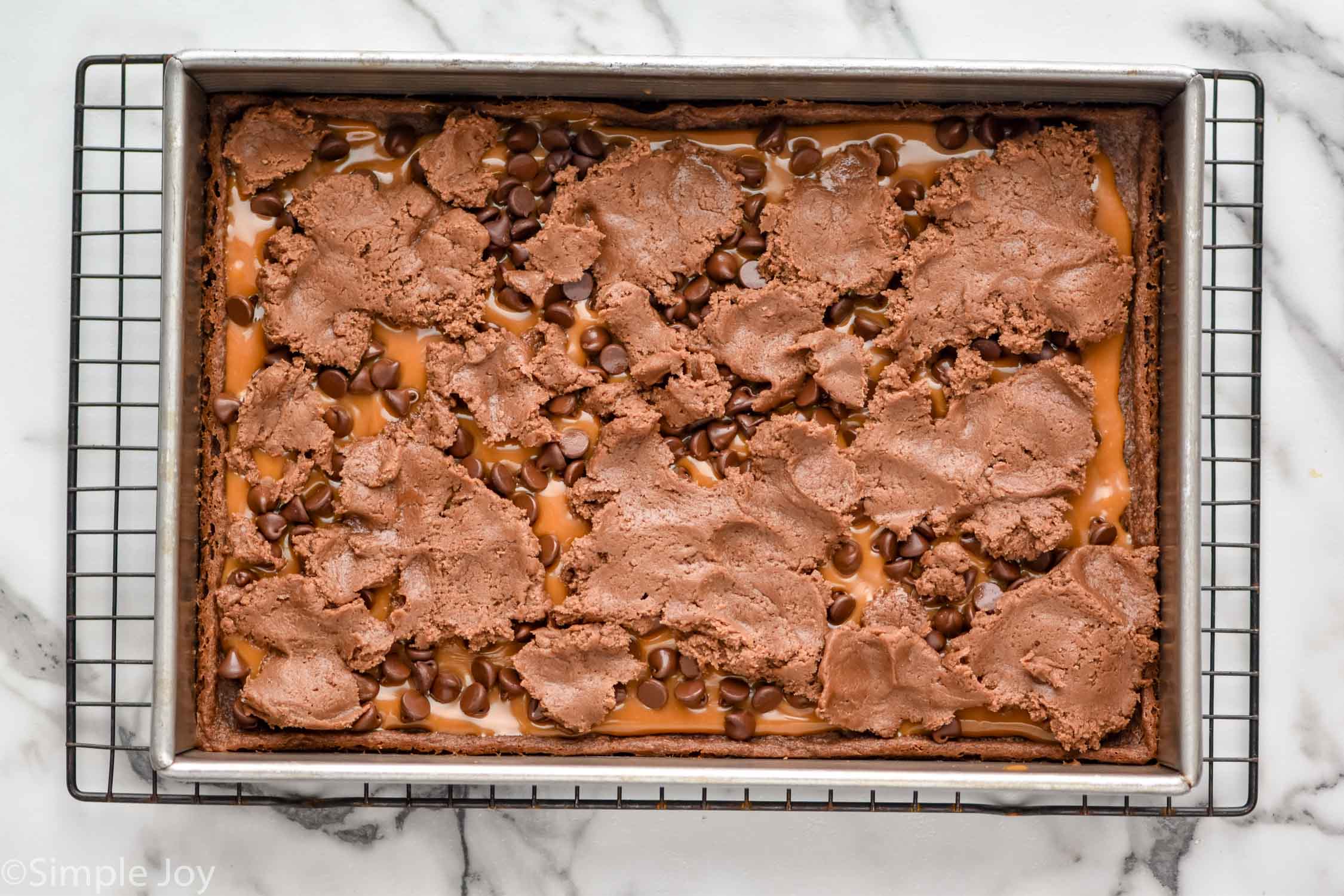 overhead of pan of caramel brownies on cooling rack ready for baking