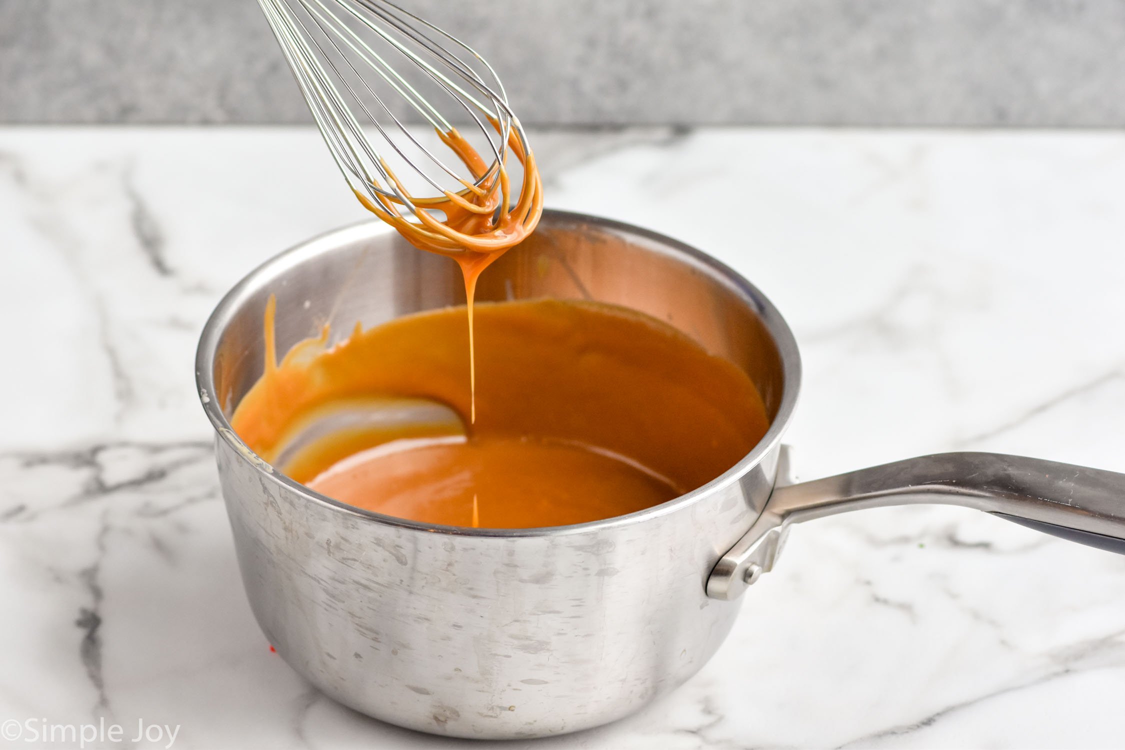 saucepan of caramel sauce for caramel brownies recipe with whisk for mixing