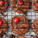 overhead view of chocolate cookies with a maraschino cherry that have been drizzled in ganache
