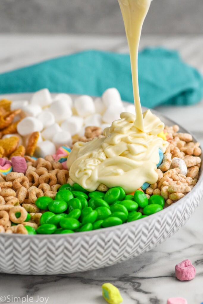 white chocolate being poured over ingredients for leprechaun bait in a bowl