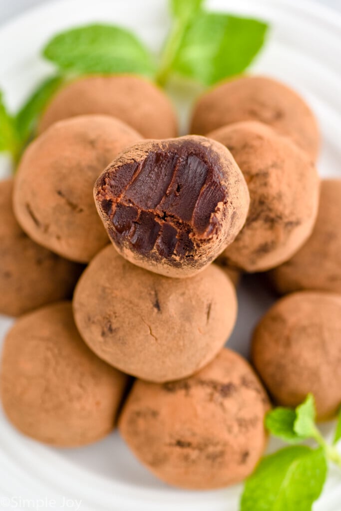 overhead of a plate of chocolate truffles with a bite missing out of the top one