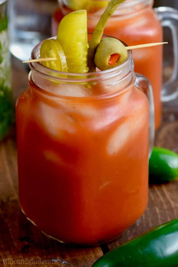 In a cold mason jar, the Bloody Mary has pickled jalapenos, pickles, olives, and asparagus on a toothpick. 