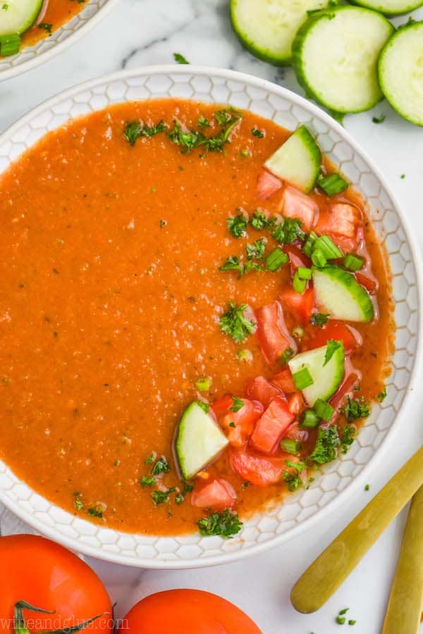 overhead view of a white bowl filled with gazpacho recipe and garnished with chopped fresh vegetables