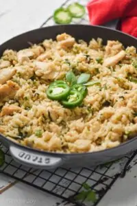 side view of a frying pan full of Thai Basil fried rice recipe garnished with Thai Basil and sliced jalapeños