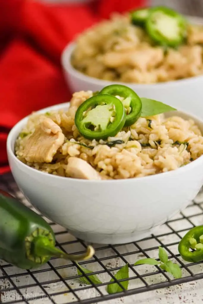 side view of a bowl of Thai Basil Fried Rice topped with two fresh jalapeños, another bowl in the background