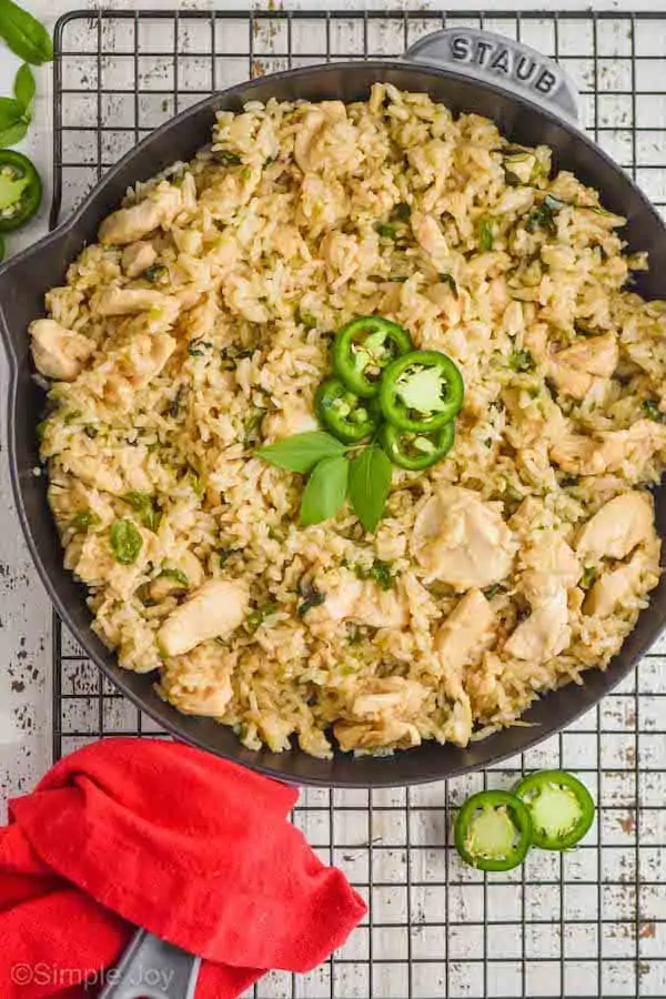 overhead view of a skillet of Thai Basil Fried Rice topped with slices of fresh jalapeños and Thai Basil leaves