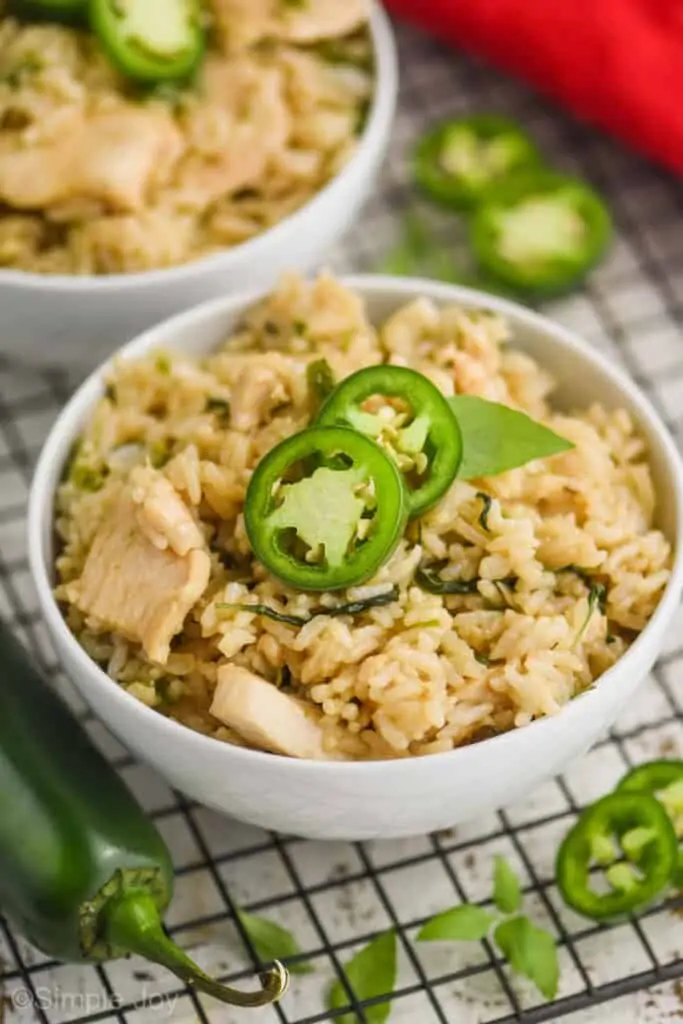 overhead view of a bowl full of Thai Basil Fried Rice topped with two slices of jalapeños and fresh Thai Basil