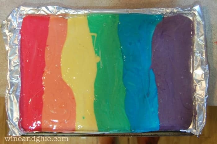 Batter is laid out on the baking sheet by the color of the rainbow. (Left to right: red, orange, yellow, green, blue, and purple)