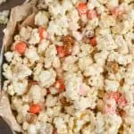 a large metal tray with parchment paper full of pumpkin spice white chocolate popcorn