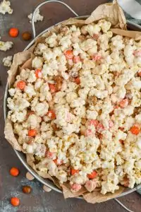 a large metal tray with parchment paper full of pumpkin spice white chocolate popcorn