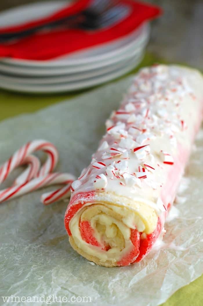 Candy Cane Cake Roll coated with frosting and sprinkled with crushed up candy cane. 