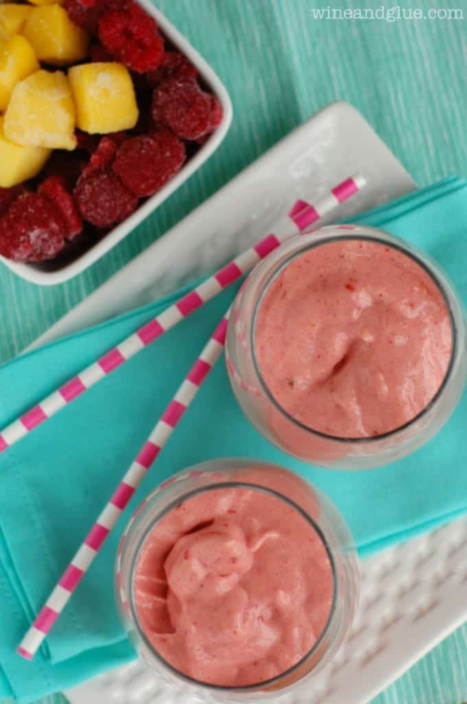 An overhead photo of two Raspberry Mango Smoothie that have a red pastel color. 