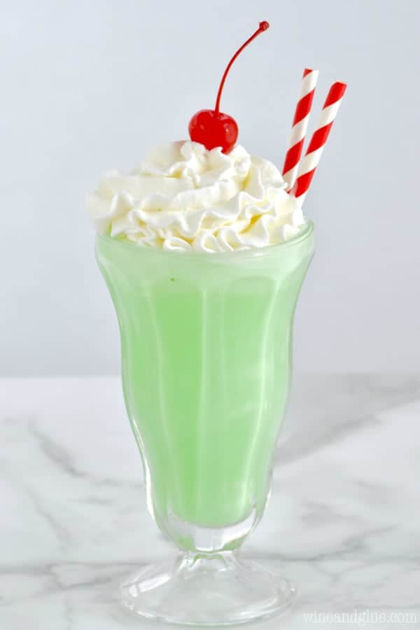 In a milkshake glass, the Copycat Shamrock Shake has a neon green color with whipped cream on top with a maraschino cherry. 