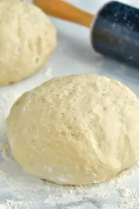 a picture of a ball of dough on a marble counter top with a rolling pin the background