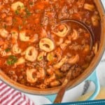 Pinterest graphic for Sausage Tortellini Soup recipe. Image is overhead photo of a pot of Sausage Tortellini Soup with a ladle for serving. Text says, "Heart Warming Tortellini Soup simplejoy.com"