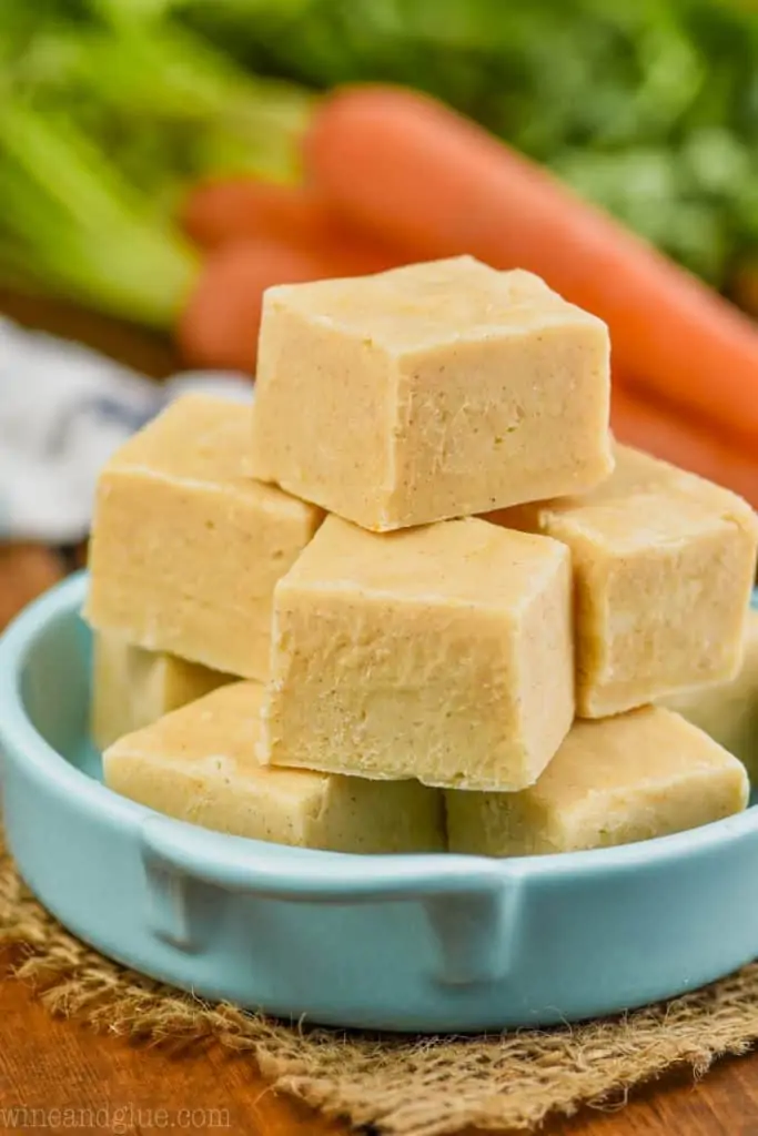 three layers of pieces of carrot cake fudge in a teal dish