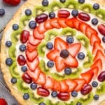 overhead view of a fruit pizza that is decorated with slices of fruit