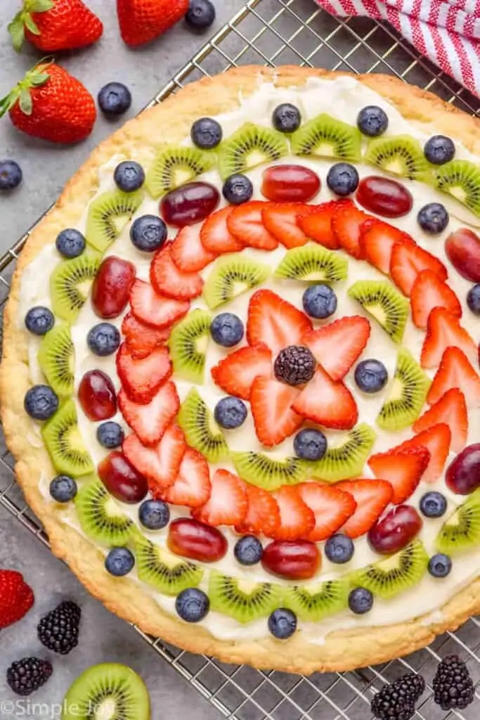 overhead view of a fruit pizza that is decorated with slices of fruit