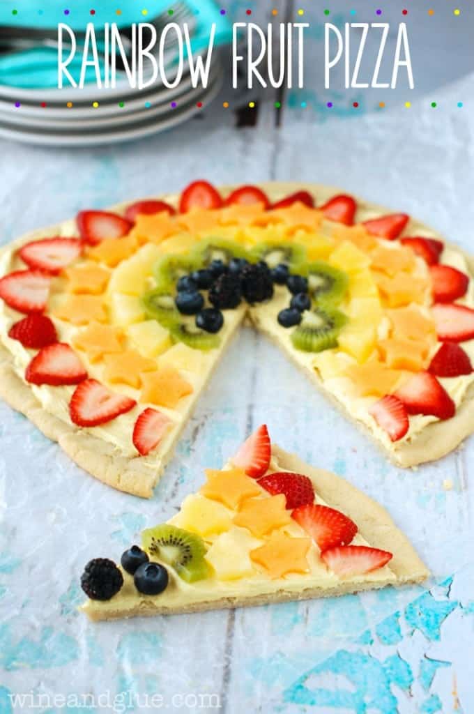 The Rainbow Fruit Pizza has a circular shape with a sugar cookie crust and cut strawberries, cantaloupe, pineapple, kiwi, blueberries, and blackberries. 
