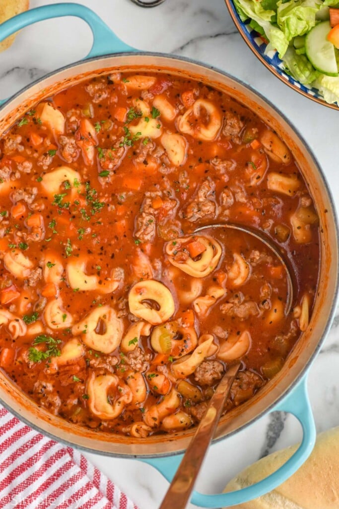 Overhead photo of Sausage Tortellini Soup in a pot with a ladle for serving.