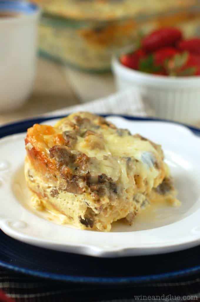 A rectangular slice of the Sausage and Mushroom Overnight Breakfast Strata has cheese oozing out. 