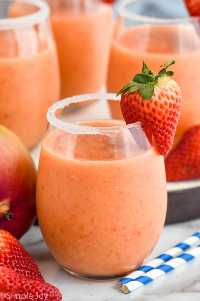 Close up photo of Strawberry Mango Margaritas served in a glass with a sugared rim and strawberry as garnish.