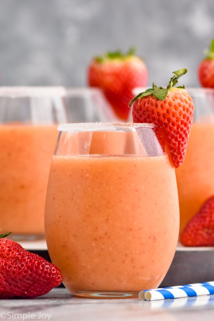 Close up photo of Strawberry Mango Margaritas garnished with strawberries and a sugared rim.