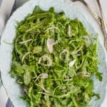 overhead view of an oval plate with an arugula salad on it