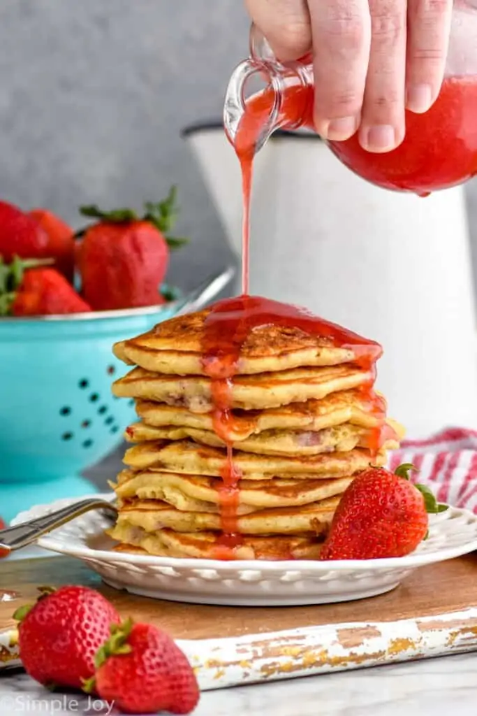 strawberry pancake syrup being poured over pancakes
