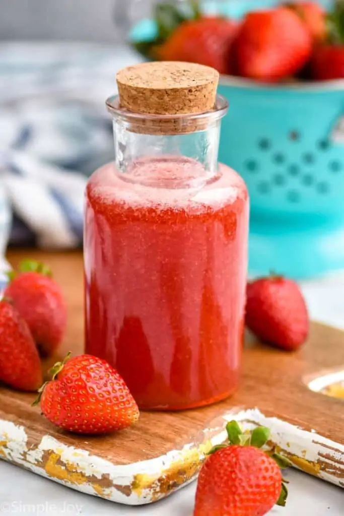 a small corked bottle holding strawberry syrup