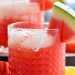 close up of a watermelon margarita with salt on the rim and a watermelon wedge on the rim
