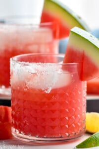 close up of a watermelon margarita with salt on the rim and a watermelon wedge on the rim