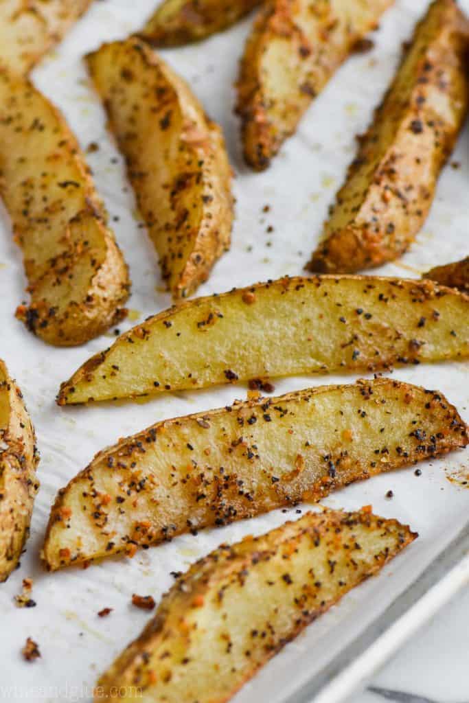 On parchment paper, the Baked Potato Wedges is beautifully seasoned and has a golden brown crust. 