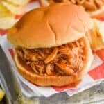 a crockpot bbq chicken sandwich on a bun with potato chips around it