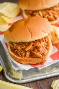 a crockpot bbq chicken sandwich on a bun with potato chips around it