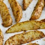 baked potato wedges that have been seasoned and are on a baking sheet