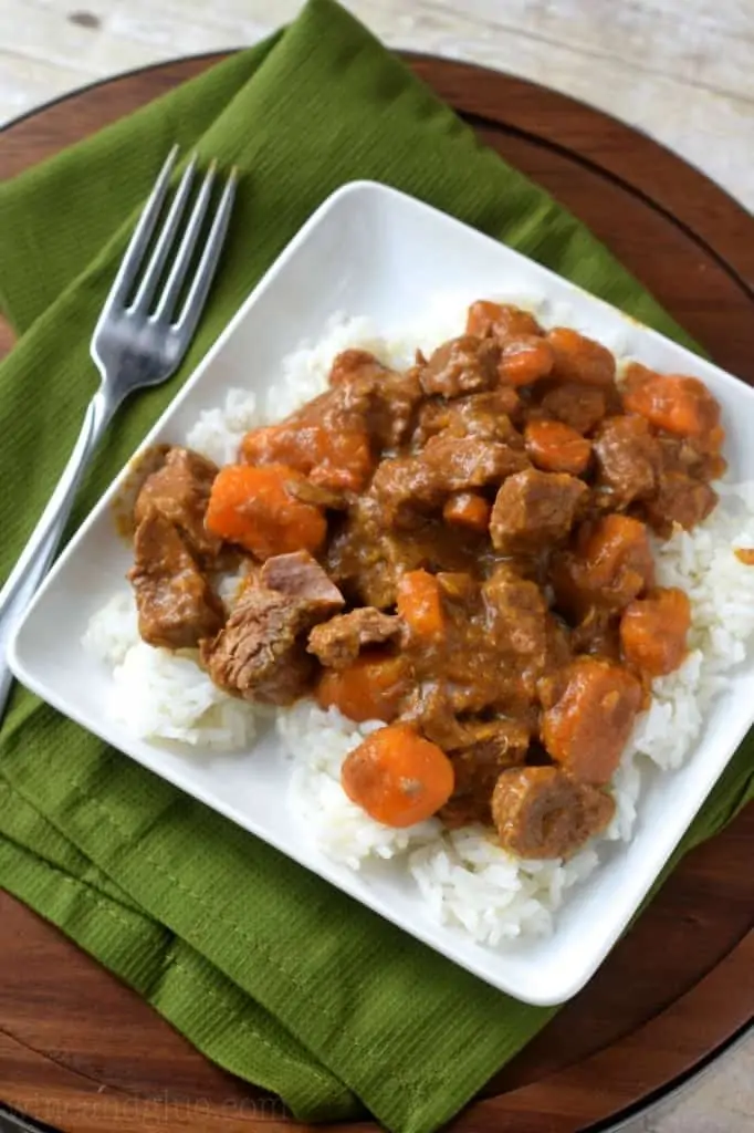 On a white plate, the Crockpot Beef Curry is on top of white rice. 