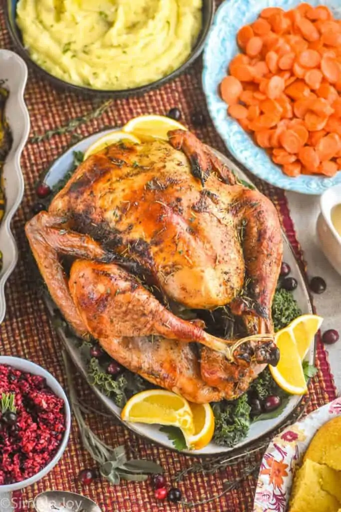 overhead view of a roast turkey on a platter surrounded by side dishes