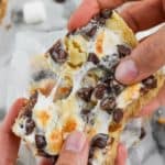 two hands pulling apart a s'mores magic bar