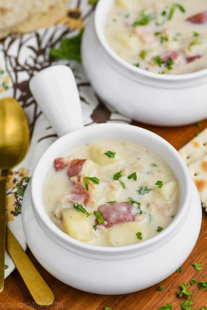 small bowl of white soup filled with New England clam soup recipe and garnished with parsley