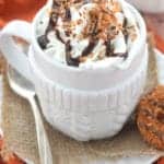 a small white mug full of a Samoa latte with whipped cream, chocolate drizzle and toasted coconut on top - 6