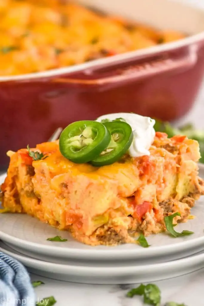 a piece of overnight breakfast casserole on a plate topped with jalapeños and sour cream