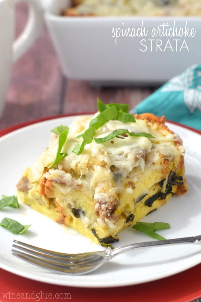 A large rectangular slice of the Overnight Spinach Artichoke Strata shows the different speckles of spinach, artichoke, and cheese. 