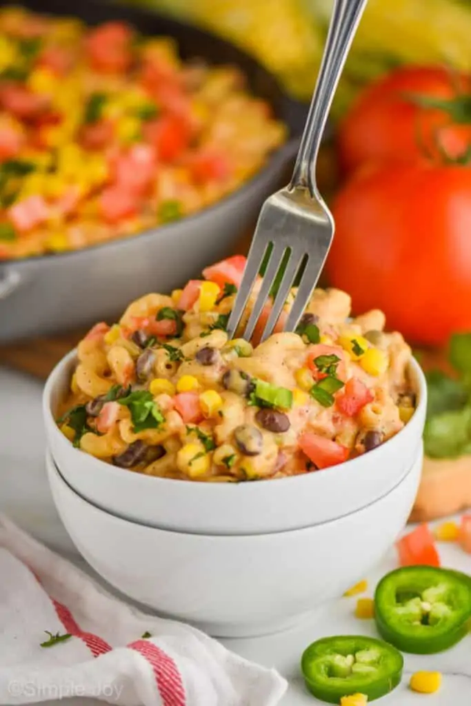 two white bowls filled with southwestern macaroni and cheese with a fork going into it