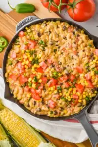 overhead view of a gray skillet filled with homemade Mac and cheese flavored with southwestern ingredients on a cutting board