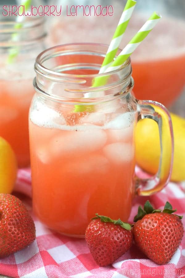In a mason jar cup, the Strawberry Lemonade has a pink tint with ice cubes. 