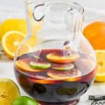 clear pitcher of the best red sangria recipe with lemons, limes, and oranges floating in it