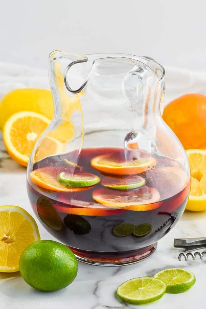 clear pitcher of the best red sangria recipe with lemons, limes, and oranges floating in it